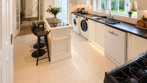 Une cuisine moderne dotée d’un îlot central, d’appareils électroménagers intégrés et offrant une vue sur l’extérieur.