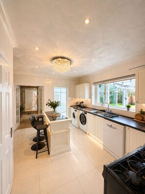 A modern kitchen with a central island, built-in appliances, and a view to the outdoors. - The Manor House | Villa style | Large Driveway (Spalding)