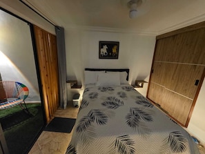 A bedroom with a bed, a chair, a small table, a nightstand, a wardrobe, and a painting on the wall. - Entire lodging at 900 meters from the village station. (Medellín)