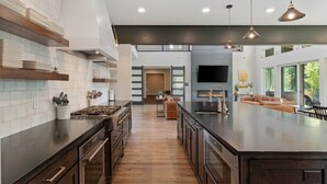 Une cuisine moderne dotée d’un grand îlot central, de meubles en bois et de luminaires suspendus.
