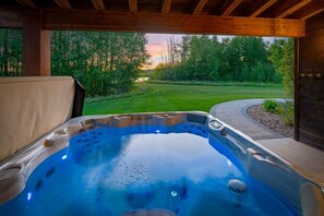 A hot tub with a view of a grassy landscape and trees.
