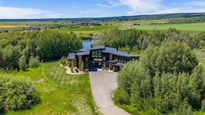 Une maison moderne dotée d’une grande allée, entourée d’une végétation luxuriante et bordée d’un lac.