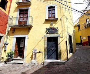 Un edificio amarillo con puerta negra, un balcón y un letrero que dice 'Mandelia'.