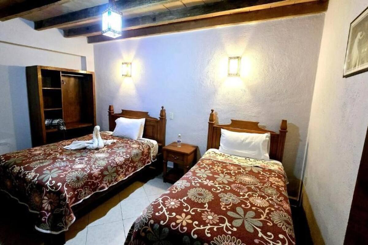 Una habitación con dos camas, un armario y una pequeña mesa.