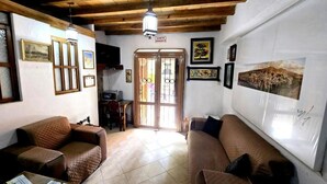 A living room with two brown sofas, a television, and a wooden ceiling. - Hotel Plaza Baratillo (Guanajuato)