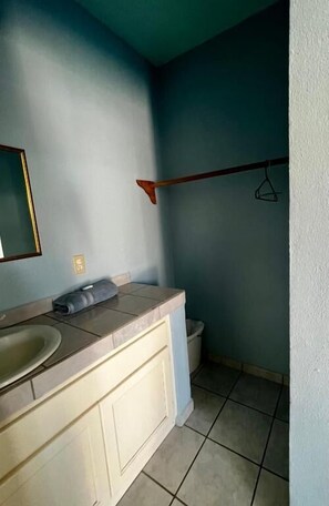 Un baño con lavamanos, espejo, toalla y perchero.