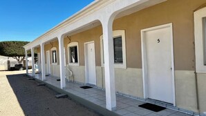 A row of single rooms with individual doors and windows, a covered outdoor area, and a clear sky. - Cozy Rooms Rocky Point - Walk to Playa Hermosa (Puerto Penasco)