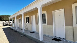 A row of single rooms with individual doors and windows, a covered outdoor area, and a clear sky. - Cozy Rooms Rocky Point - Walk to Playa Hermosa (Puerto Penasco)