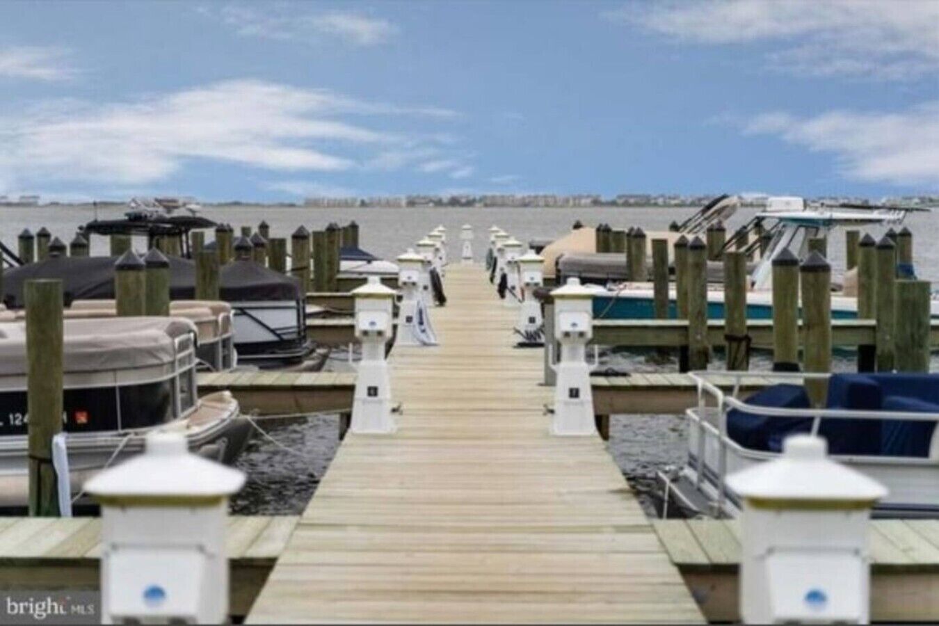 A pier with boats docked on both sides, leading to a waterfront area.