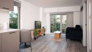 Una sala moderna con sofá, mesa de centro, televisor y un mueble bajo.