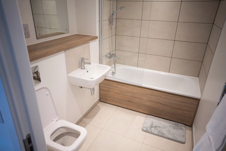 A bathroom with a toilet, sink, and bathtub.. Church Street Place