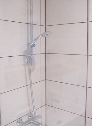 A shower with a handheld showerhead and a wall-mounted faucet.