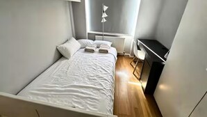 Een slaapkamer met een bed, bureau en radiator.