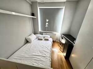 Ein Schlafzimmer mit einem Bett, einem Schreibtisch und einer Heizung.