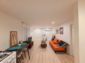 Ein Wohnzimmer mit Sofa, Esstisch, Fernseher und Kamin.
