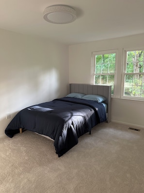 Een slaapkamer met een bed, een raam en een plafondlamp.