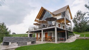 A modern multi-level house with outdoor seating and a stone fireplace. - Paseo del Llano Grand Cabañas (Mazamitla)