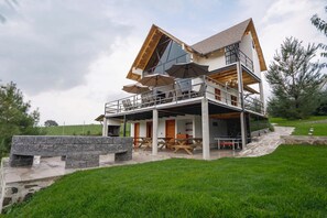 A modern multi-level house with outdoor seating and a stone fireplace. - Paseo del Llano Grand Cabañas (Mazamitla)