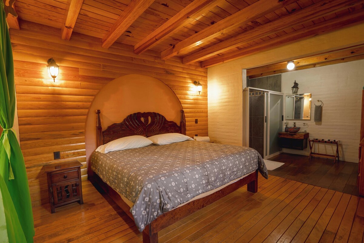 A wooden-paneled bedroom with a bed, bedside tables, and a mirror.