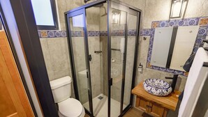 A bathroom with a glass-enclosed shower, a toilet, and a sink with a decorative basin. - Paseo del Llano Grand Cabañas (Mazamitla)