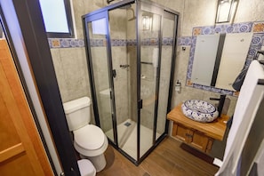 A bathroom with a glass-enclosed shower, a toilet, and a sink with a decorative basin. - Paseo del Llano Grand Cabañas (Mazamitla)