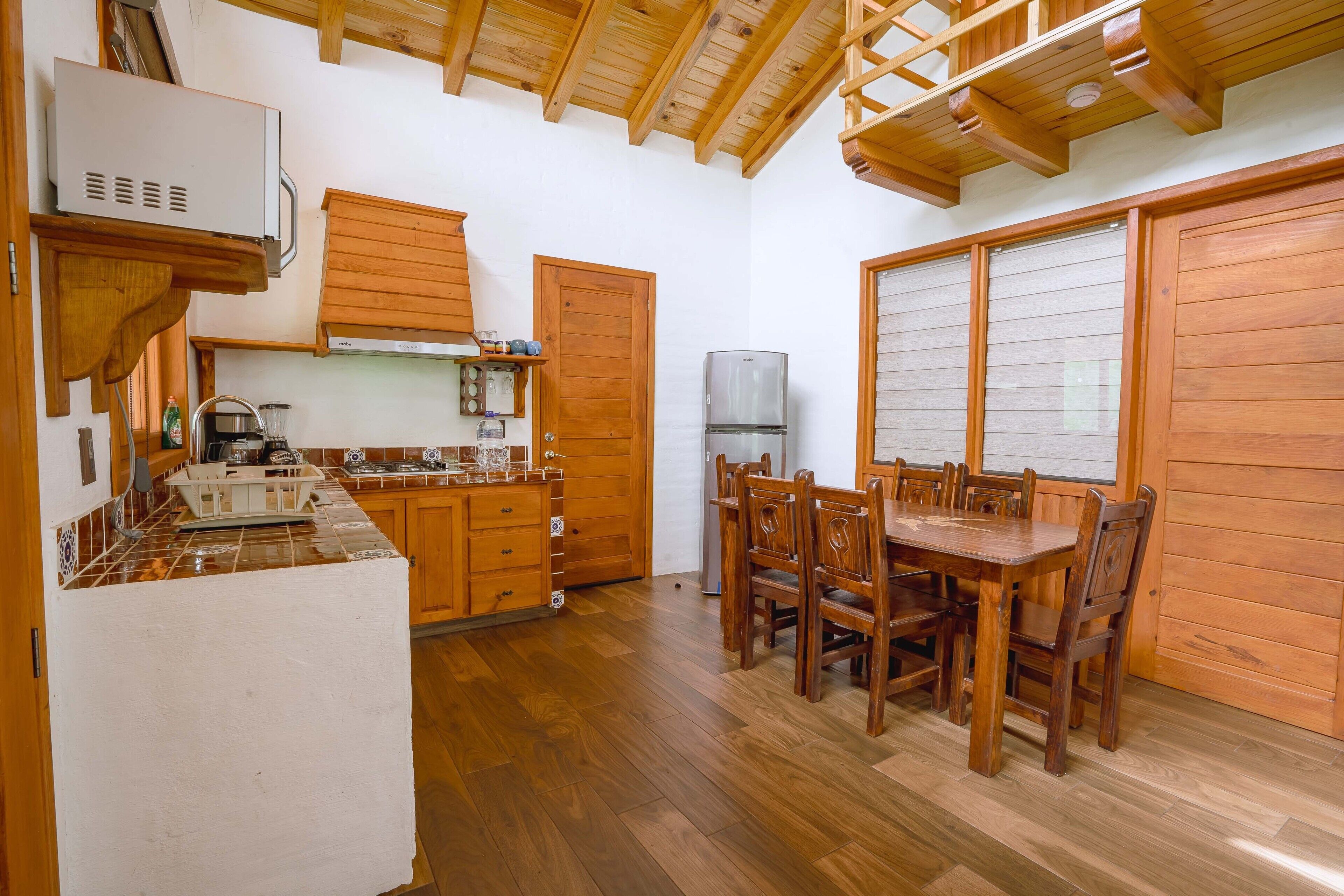 Cocina pequeña con armarios de madera, una mesa de comedor y sillas.