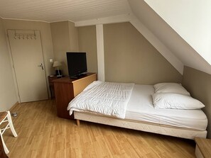 A bedroom with a bed, a desk with a TV, a chair, and a door. - Vacation Rental in the Heart of Saint-Cast - 80 m from Grande Plage   (ST CAST LE GUILDO)