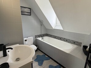 A modern bathroom with a skylight, a bathtub, a toilet, and a sink. - Vacation Rental in the Heart of Saint-Cast - 80 m from Grande Plage   (ST CAST LE GUILDO)