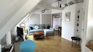 Un appartamento in stile loft con soffitto alto, un divano blu, un tavolino in legno e un'area pranzo.