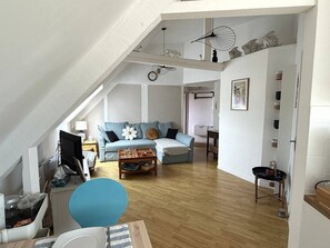Eine Loft-Wohnung mit hohen Decken, einem blauen Sofa, einem Holztisch und einem Essbereich.