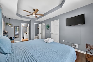 A bedroom with a bed, ceiling fan, TV, and a door leading to a bathroom. - 15 min to Truist, King Bed, Kid-Friendly, Fire Pit (Marietta)