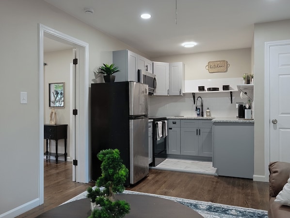 A modern kitchen with grey cabinets, a black refrigerator, and a microwave.