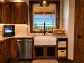 Una cocina con armarios de madera, horno empotrado, un lavamanos y una ventana con vistas.