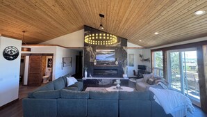 Een moderne woonkamer met een ruime hoekbank, een open haard en een houten plafond.