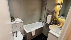A modern bathroom with a bathtub, a sink, a toilet, and a shower. - Fitzrovia 2 bedroom flat near the Britain museum (London)