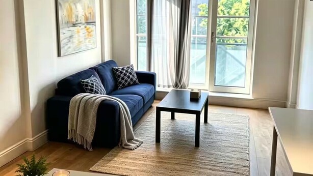 A modern living room with a sofa, a coffee table, a small table, and a potted plant. - Fitzrovia 2 bedroom flat near the Britain museum (London)