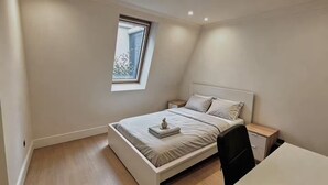A bedroom with a bed, bedside tables, a desk, and a window. - Fitzrovia 2 bedroom flat near the Britain museum (London)