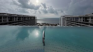 A hotel with an infinity pool overlooking the ocean, multiple balconies, and a clear view of the sea. - Garza Blanca Resort: Spacious 1,830 sq ft 2-bedroom suite for up to 6 guests. (Cancún)