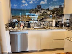 Eine moderne KĂŒche mit GeschirrspĂŒler, Kaffeemaschine, Toaster und Mixer.