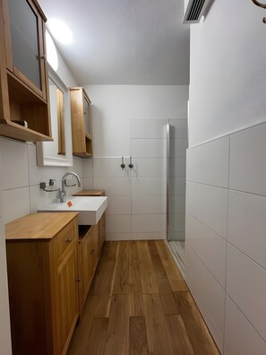 Ein modernes Badezimmer mit einem Holzkosmetikschrank, einem Waschbecken und einer Duschkabine aus Glas.