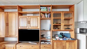 Eine Holz-Multifunktionswand mit Flachbildfernseher, Bücherregalen und Spielkonsolen.