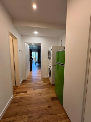 Ein Flur mit Holzboden, einer Waschmaschine und einem Kühlschrank.
