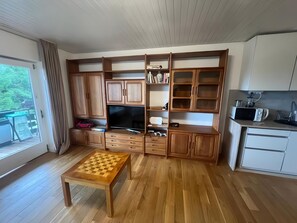 Un vaste espace de vie dotĂ© de meubles en bois, dâun tĂ©lĂ©viseur Ă Ă©cran plat, dâune table basse et dâun coin cuisine Ă©quipĂ© dâun four Ă micro-ondes.