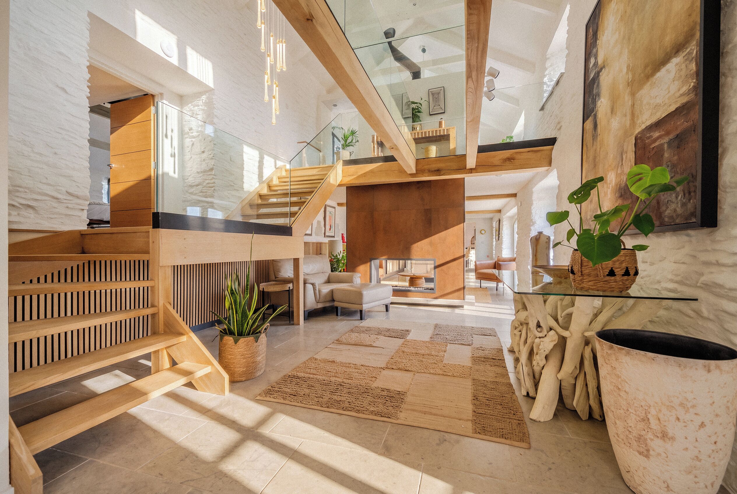 A spacious interior with a high ceiling, wooden staircase, and a central seating area with a glass coffee table.