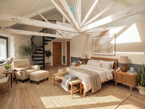 Ein Schlafzimmer mit einem Bett, einem Sessel, einem Nachttisch, einer Lampe, einer Pflanze, einem Bücherregal und einer Treppe.