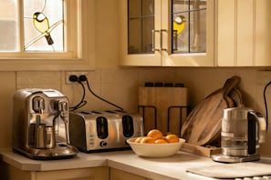 Eine Küche mit Kaffeemaschine, Toaster und einer Schale Orangen auf der Arbeitsplatte.