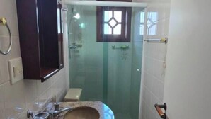 Ein Badezimmer mit Marmorwaschbecken, einer Duschkabine aus Glas und einem dunklen Korpus.