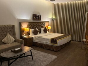 Ein Hotelzimmer mit Bett, Sofa, Couchtisch, Nachttisch und Lampe.