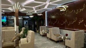 Una hall con poltrone trapuntate, una moquette decorata e un muro con calligrafia.