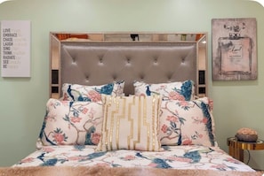 A bed with floral bedding, a tufted headboard, and decorative pillows.